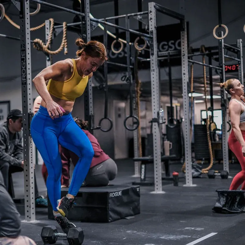 A coach guiding a member through box step-ups at Kalamazoo Strength